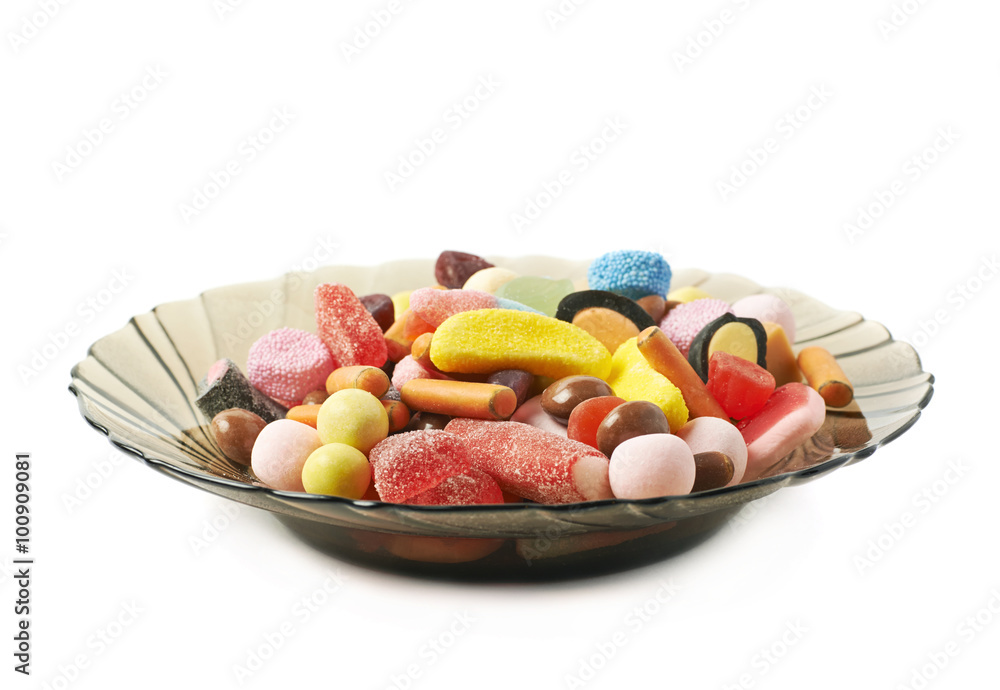 Glass plate full of candies isolated