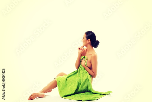 Laughing woman sitting wrapped in towel 