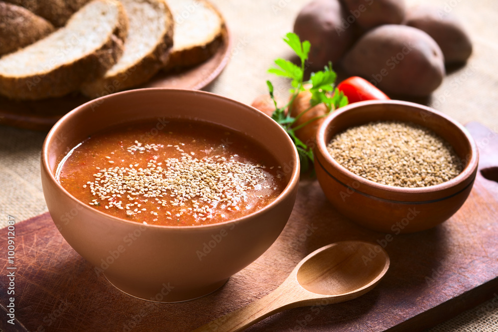 Cream of vegatable soup made of tomato, carrot, potato and parsley served in bowl and sprinkled with sesame seeds, photographed with natural light (Selective Focus, Focus in the middle of the soup) Cream of vegatable soup made of tomato, carrot, potato and parsley served in bowl and sprinkled with sesame seeds, photographed with natural light (Selective Focus, Focus in the middle of the soup)
