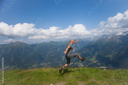 man jumping off a cliff in the mountains in summer
