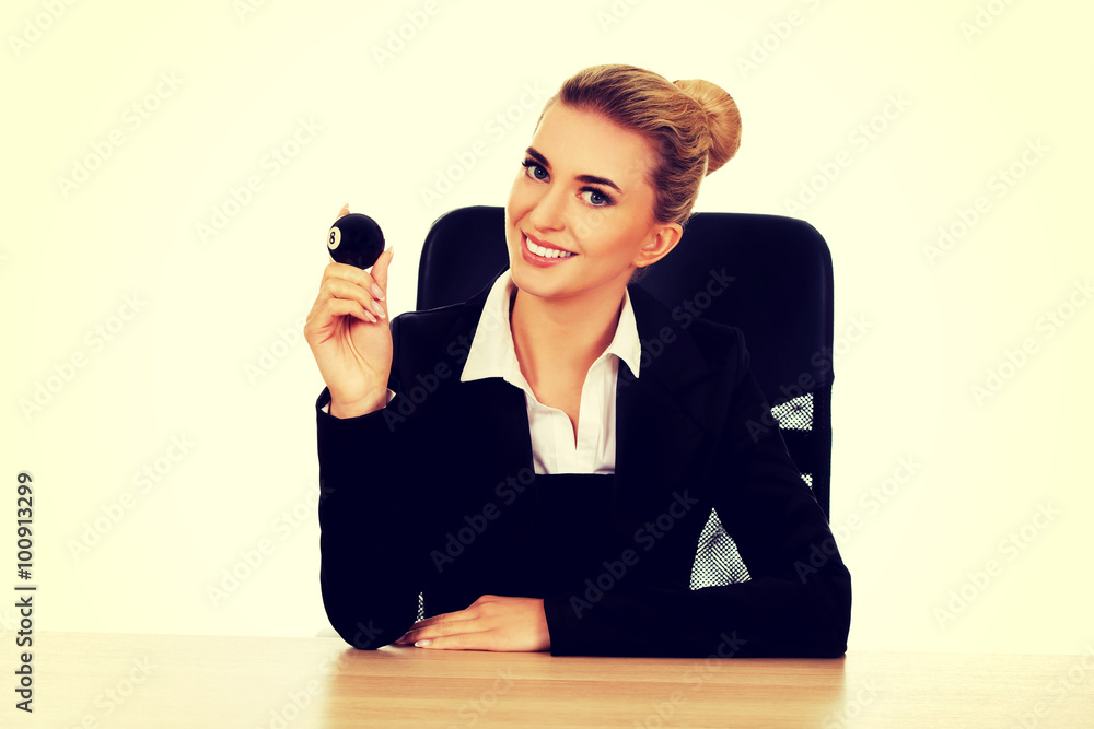 Businesswoman holding eight billiard ball by a desk Businesswoman holding eight billiard ball by a desk