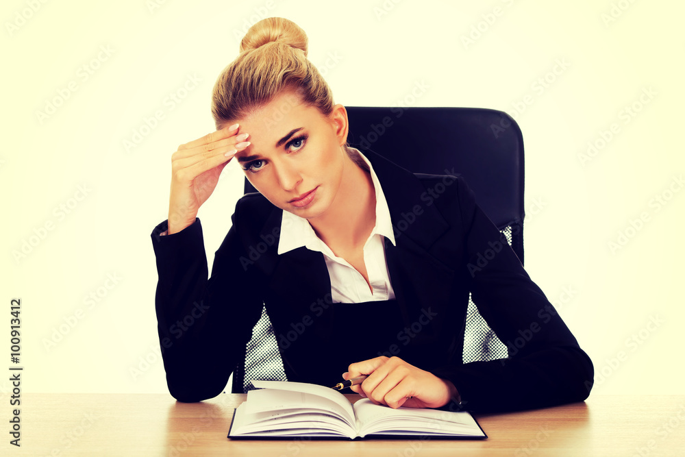 Tired businesswoman writing note by a desk Tired businesswoman writing note by a desk
