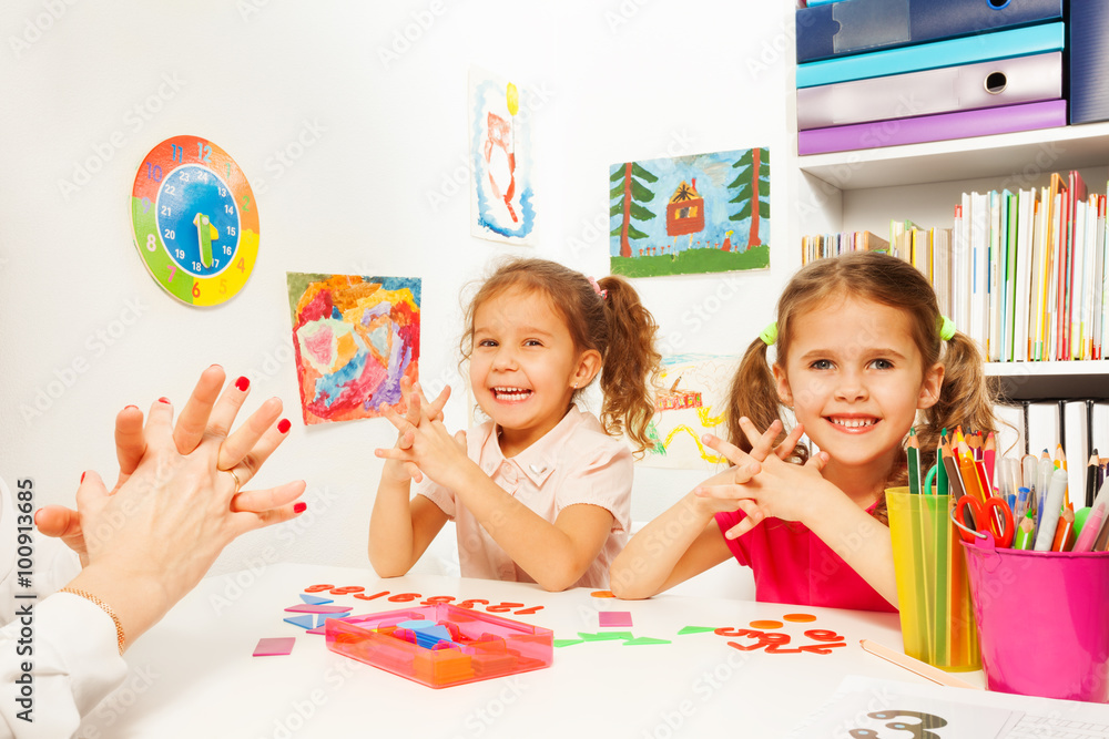 Fototapeta premium Two girls doing finger exercises as her teacher