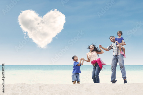 Happy family at beach under heart cloud