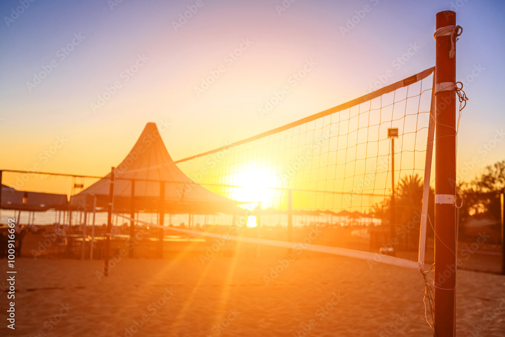 Sillhouette of a volleyball net and sunrise on the beach