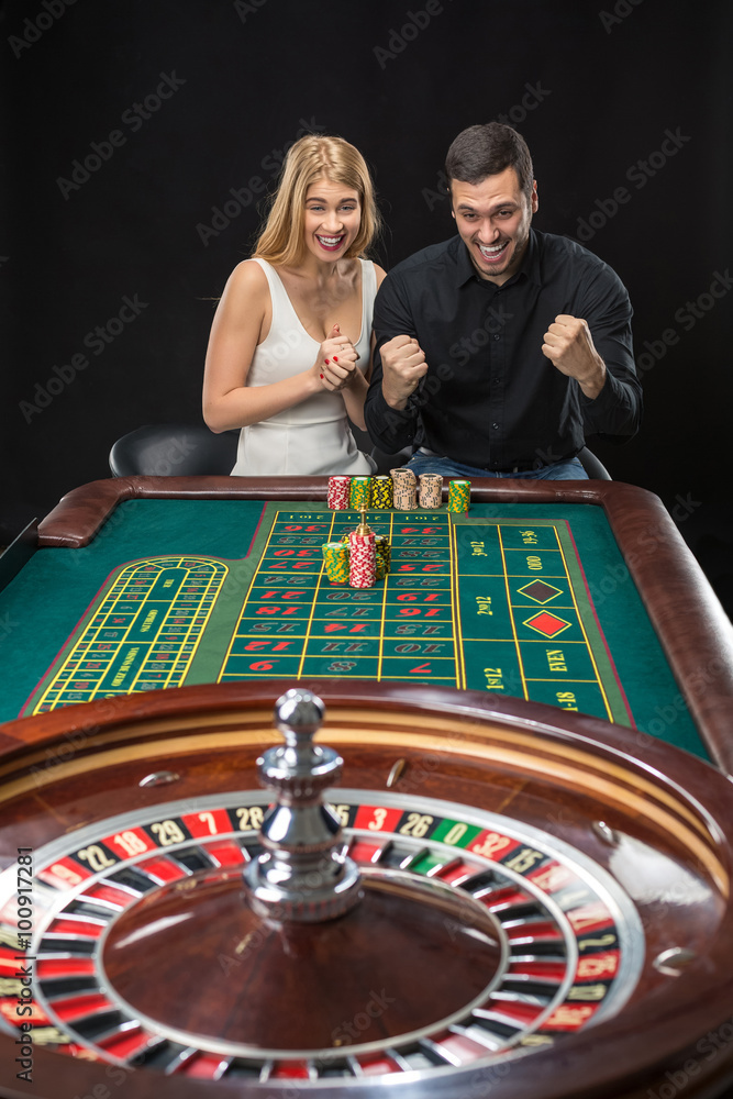 Man and woman cheering at roulette table in casino Man and woman cheering at roulette table in casino