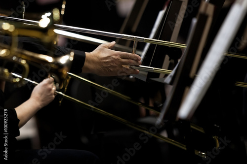 Hands of musicians played the trombone in the orchestra in dark colors