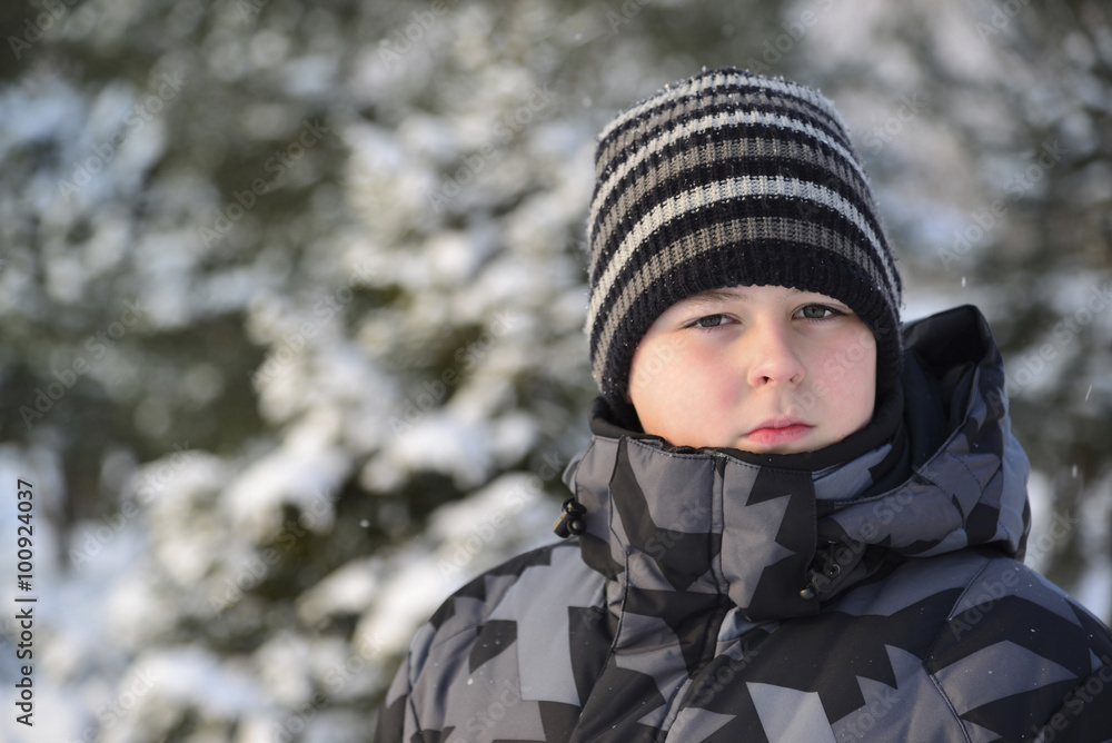 Portrait of serious teenage boy at a pine forest in winter Portrait of serious teenage boy at a pine forest in winter