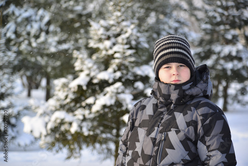 Portrait of serious teenage boy at a pine forest in winter