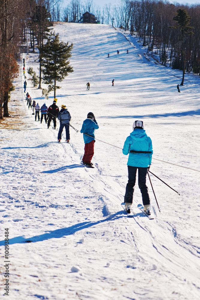 .Skiers going uphill on ski lift.
