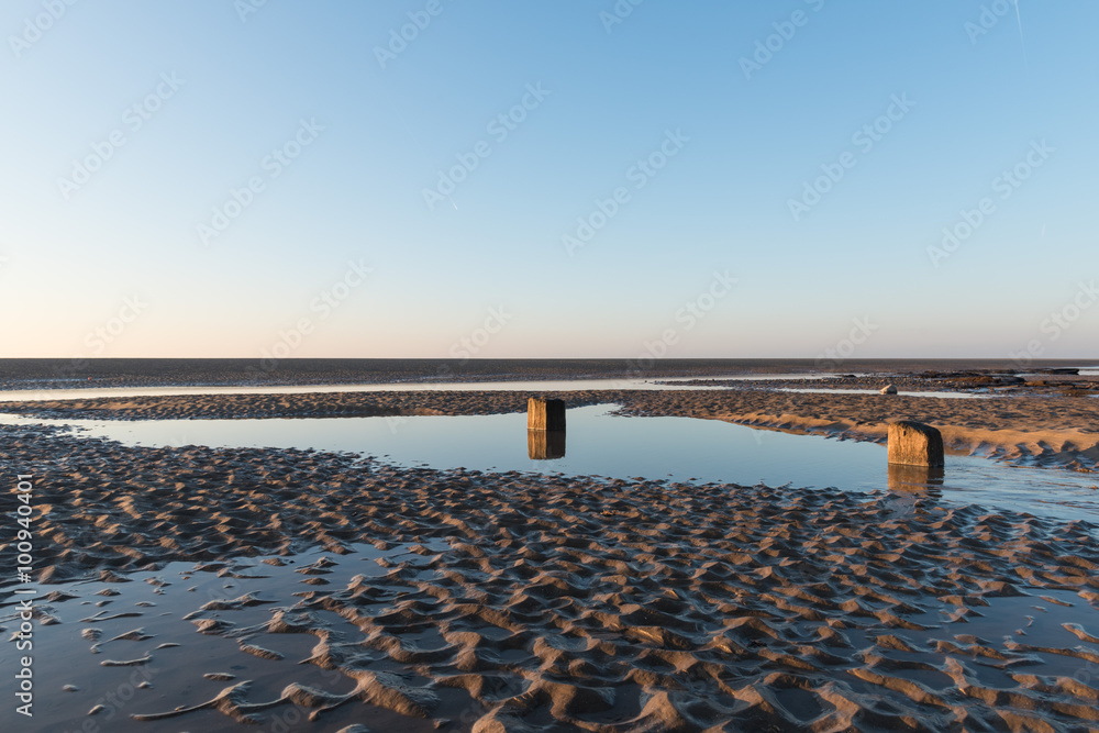 Beautiful sunny winters day on a british beach, with sand ripples and the sky reflecting in a water pool.
