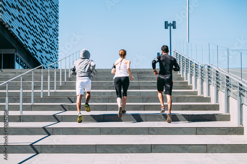 Three young friends running on the steps of a building