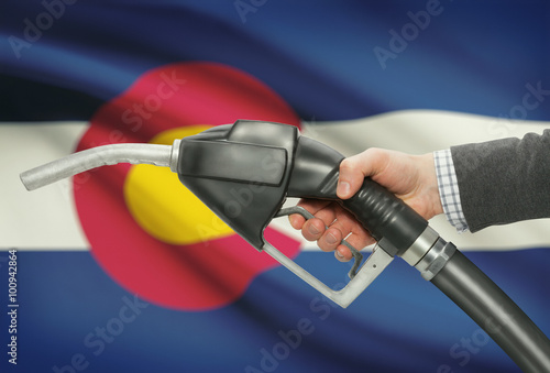 Fuel pump nozzle in hand with USA states flags on background - Colorado photo