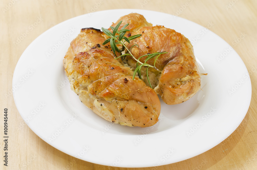 Spicy baked chicken breast with rosemary entirely on a plate