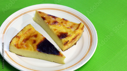 Dessert: Piece of Parisian Flan or French Custard Pie on white plate and green background