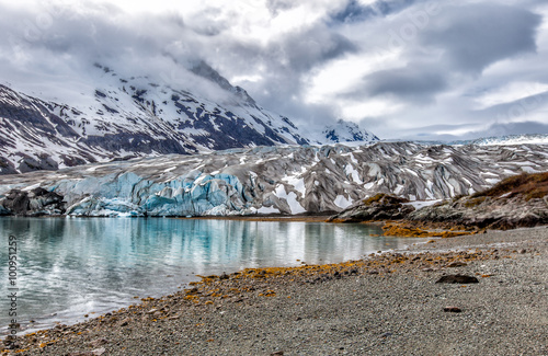 Alaska glacier landscape with reflections in a blue lake of melted water. Climate change impact photo