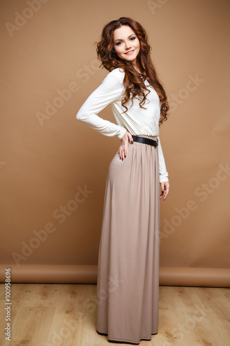 Close-up portrait of beautiful sexy young woman with long brown hair over brown background