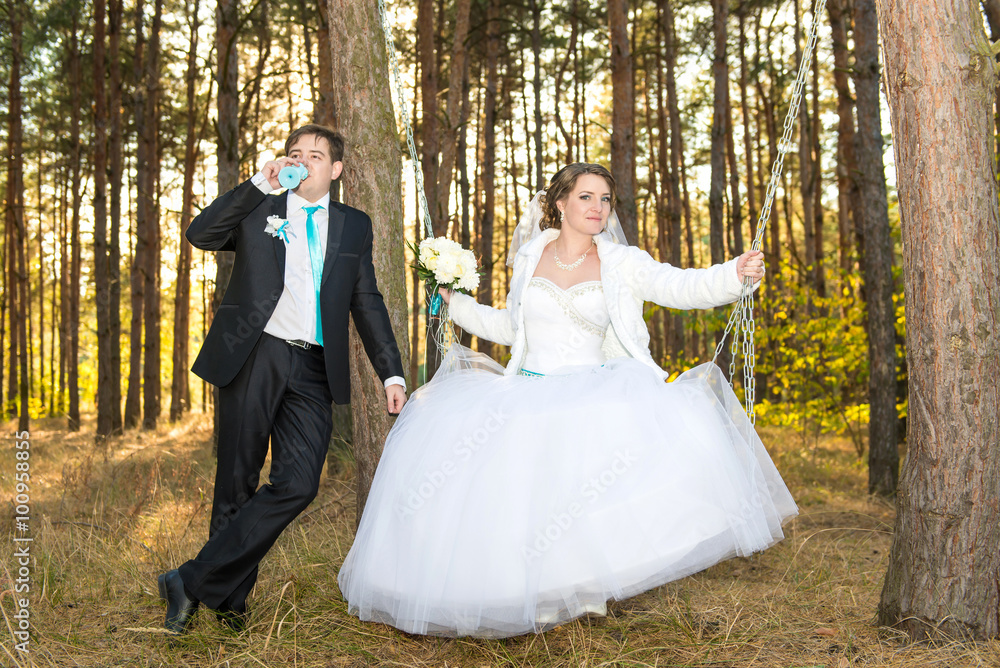 Groom rolls bride on a swing in the woods