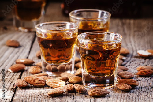 Fotografía Italian amaretto liqueur with dry almonds on the old wooden back