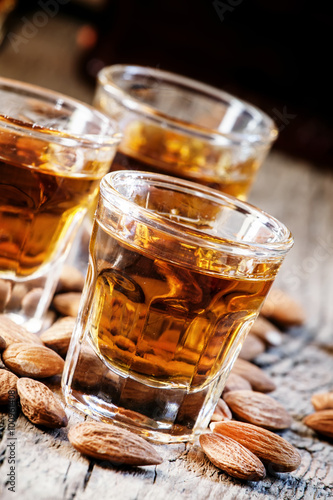 Italian amaretto liqueur with dry almonds on the old wooden back