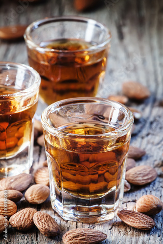 Italian amaretto liqueur with dry almonds on the old wooden back