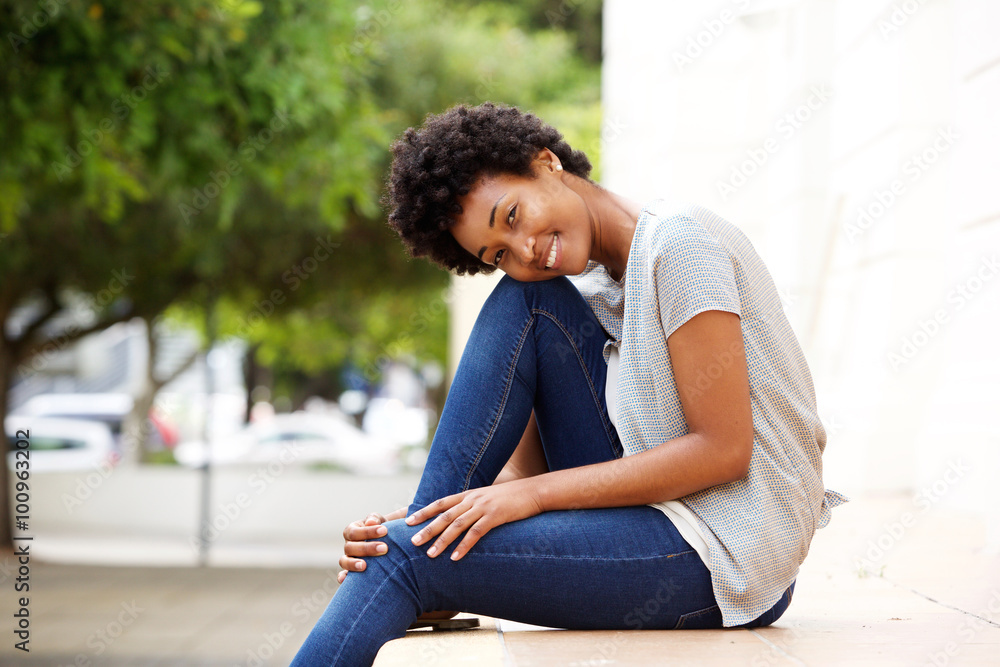 Beautiful young african woman sitting by a city street Beautiful young african woman sitting by a city street