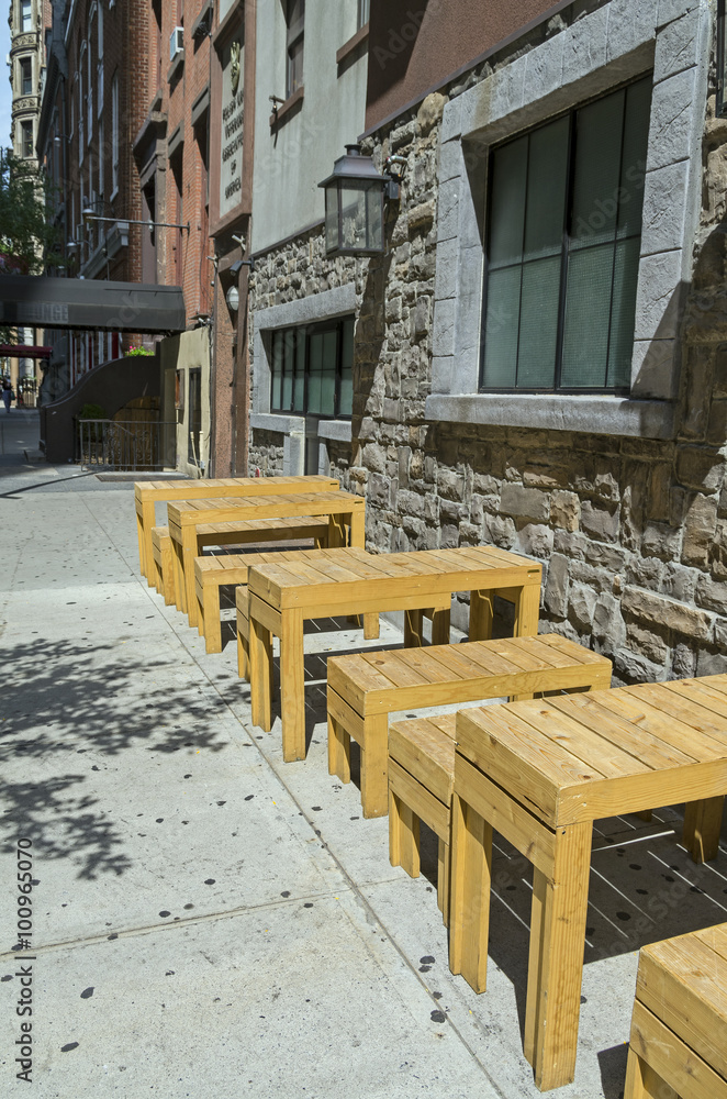 Wooden tables and benches on a city street.