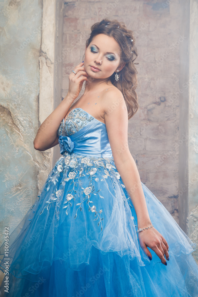 Beautiful young woman in gorgeous blue long dress like Cinderella with perfect make-up and hair style Beautiful young woman in gorgeous blue long dress like Cinderella with perfect make-up and hair style