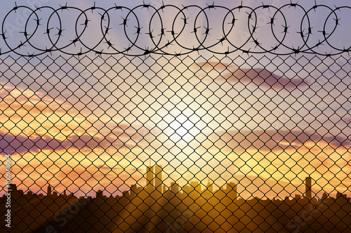 Silhouette of city and fence