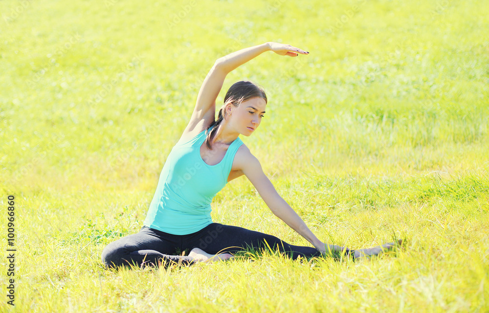Woman doing yoga exercises on grass in summer day Woman doing yoga exercises on grass in summer day