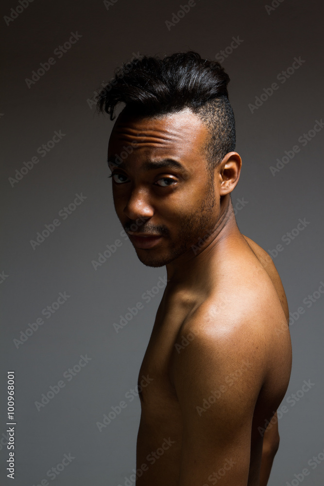 Latin man posing indoor over a grey wall. Latin man posing indoor over a grey wall.