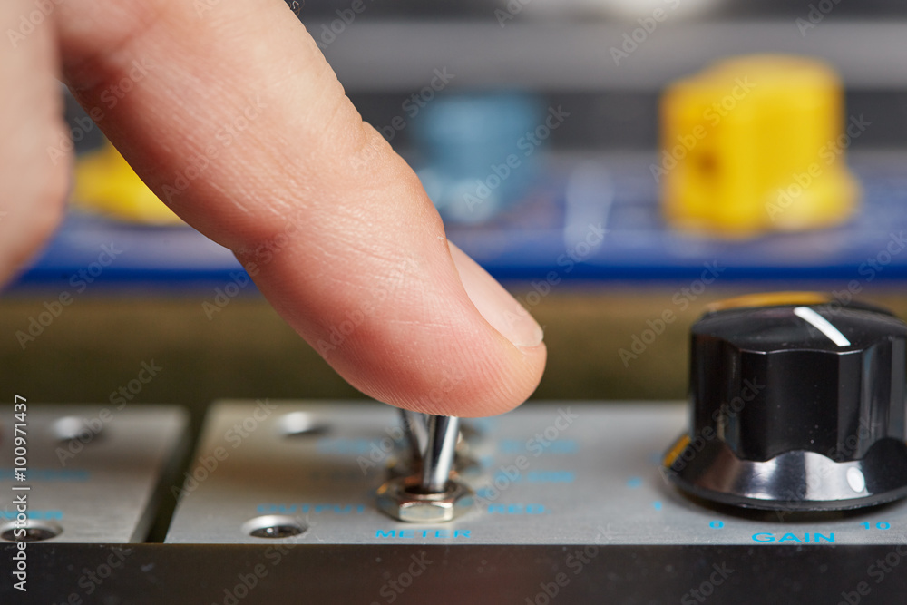 Finger of a man on a switch on some audio hardware Finger of a man on a switch on some audio hardware