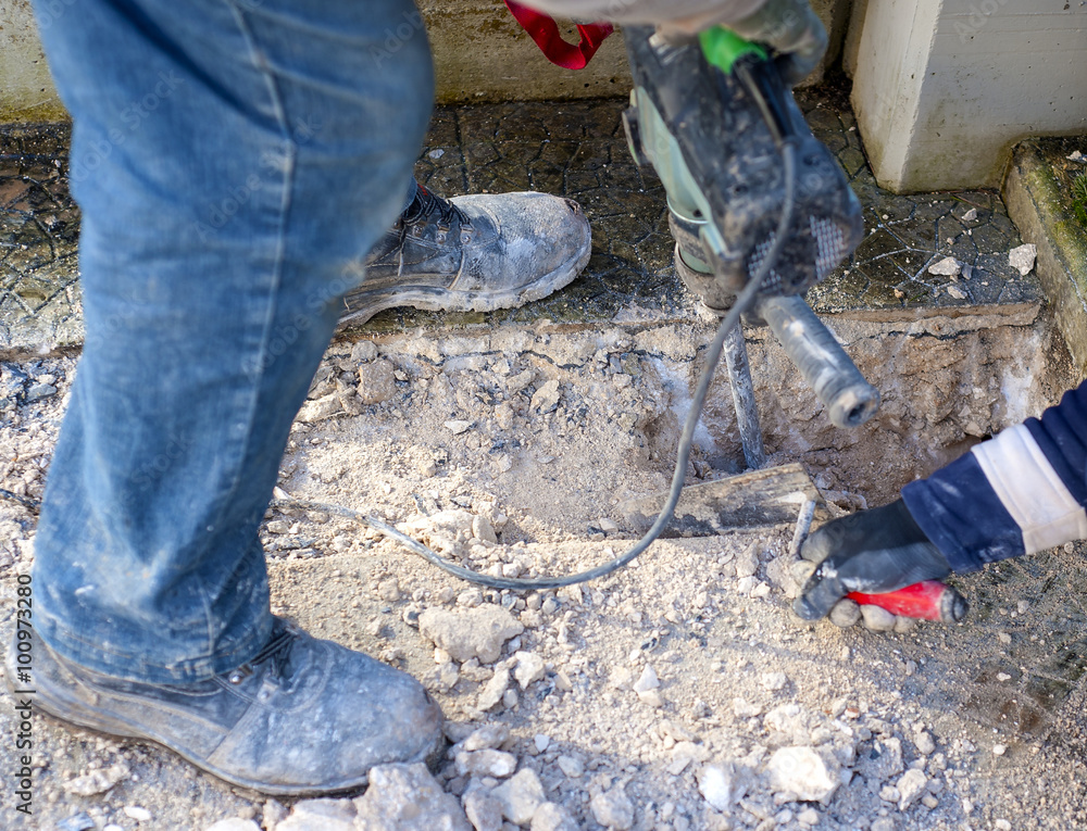 Construction site - workers using Jackhammer and trowel performing track on the floor sidewalk.Selective focus and motion blur Construction site - workers using Jackhammer and trowel performing track on the floor sidewalk.Selective focus and motion blur