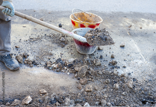 Wallpaper Mural cleaning rubble from the road, worker works with a shovel and bucket Torontodigital.ca