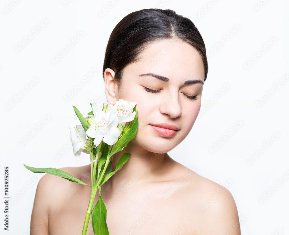 beautiful girl touching her cheeks to flower during spa