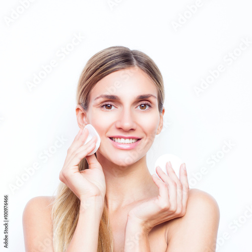 Woman with smile with teeth removes makeup with cotton pad. Beauty concept.