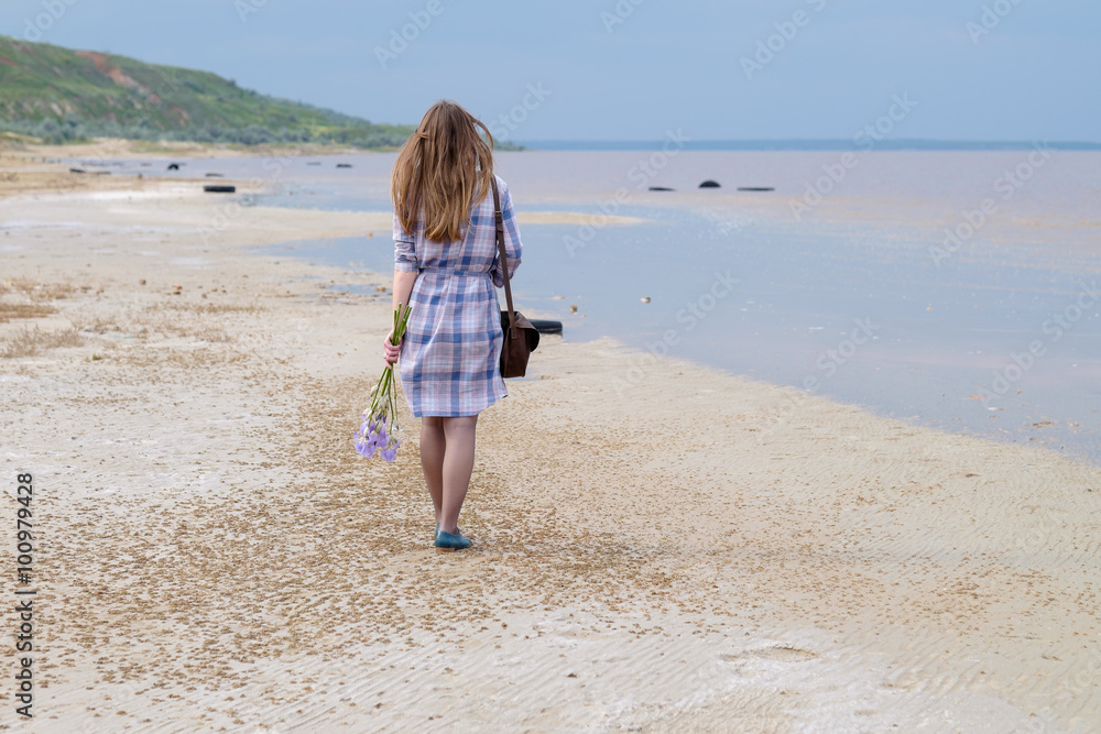 Young Caucasian woman walking along a beach