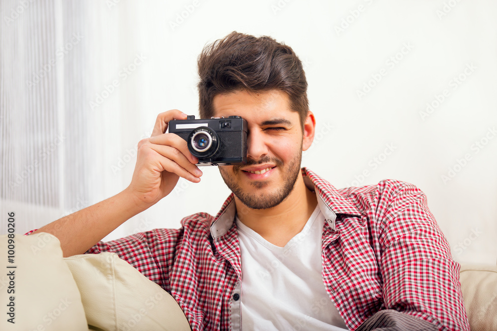 Man holding retro camera, sitting on sofa at home Man holding retro camera, sitting on sofa at home