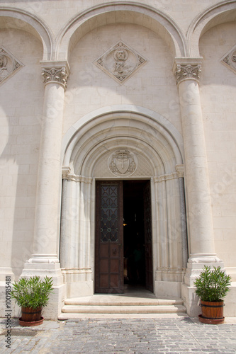 Beautiful entrance of a white church in Hungary with two pots with plants
