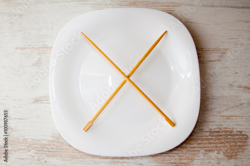 various sushi on white plate with chopsticks at wooden background
