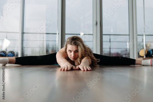 Woman doing stretching exercises on karemat in fitness center