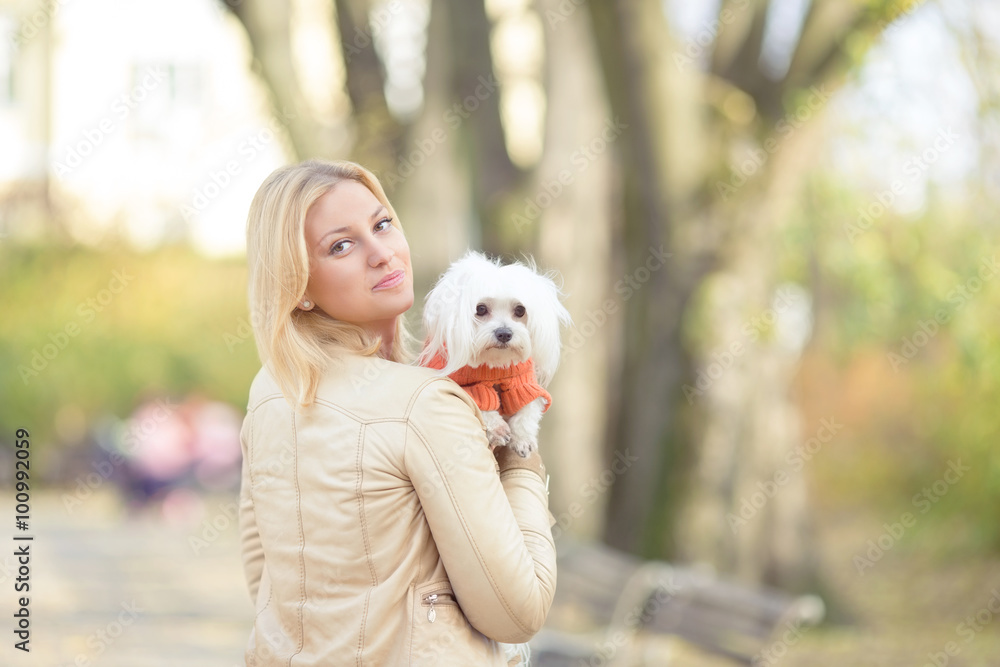 Portrait of a beautiful young woman carrying her cute little Maltese dog Portrait of a beautiful young woman carrying her cute little Maltese dog