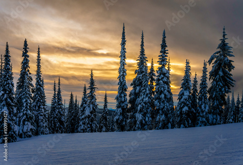 Sunset over the ski hills at Sun Peaks village with trees covered in snow in the high alpine mountains near the village of Sun Peaks in the Shuswap Highlands of central British Columbia, Canada