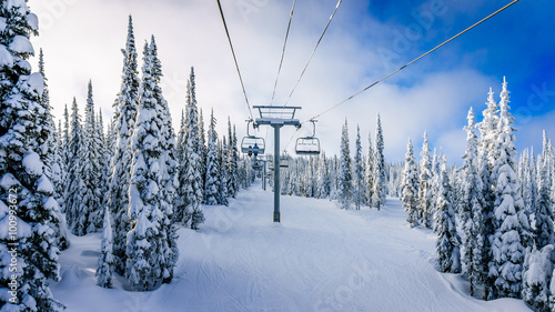 Alpine ski lift and snow covered pistes and trees on a cold winter day under beautiful sky on Mount Morrisey at the village of Sun Peaks in the Shuswap Highlands of central British Columbia