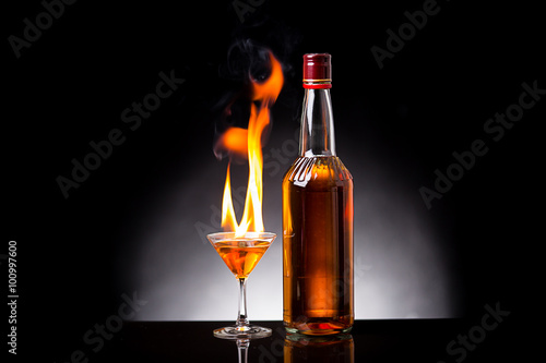 wine glass with burning alcohol on black background