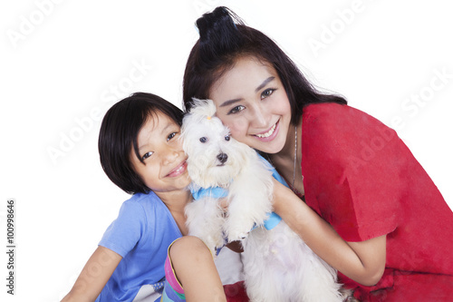 Woman and her daughter hugging maltese dog