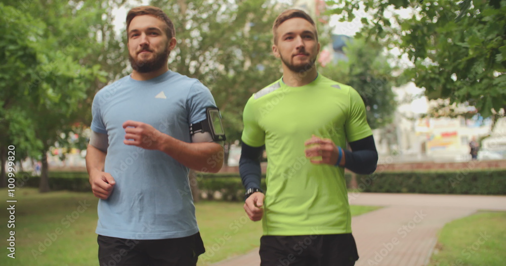 Sporty twin brothers jogging in park in summertime Sporty twin brothers jogging in park in summertime