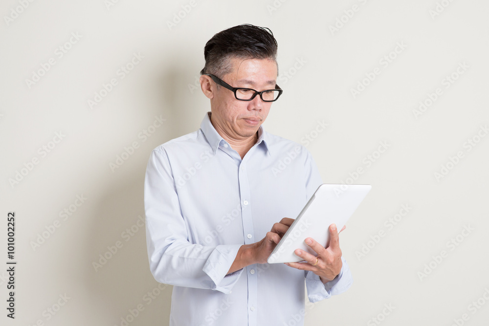 Portrait of mature Asian man using tablet pc Portrait of mature Asian man using tablet pc