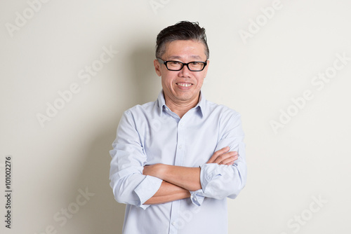 Portrait of mature Asian man arms crossed and smiling