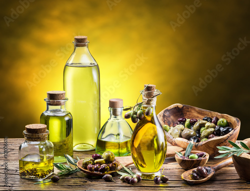 Glass bottles of olive oil and few berries on the wooden table.